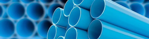 Image of blue PVC pipes stacked together, highlighting their smooth cylindrical shape. These pipes are typically used in conjunction with conical extruders for manufacturing and polymer processing applications