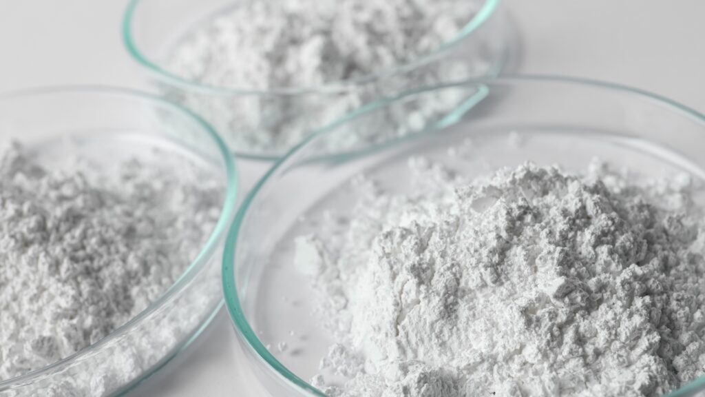 Close-up image of fine calcium carbonate powder in glass dishes, commonly used as filler material in compounding and plastic extrusion processes.