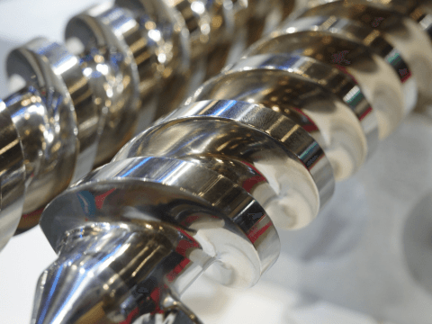 Close-up of a polished conical extruder screw at IBF Japan 2023.