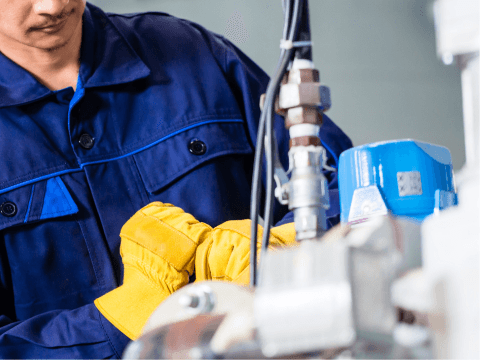 CTE maintenance team member in protective gear performing maintenance work on machinery, focusing on ensuring the operational integrity of industrial equipment.