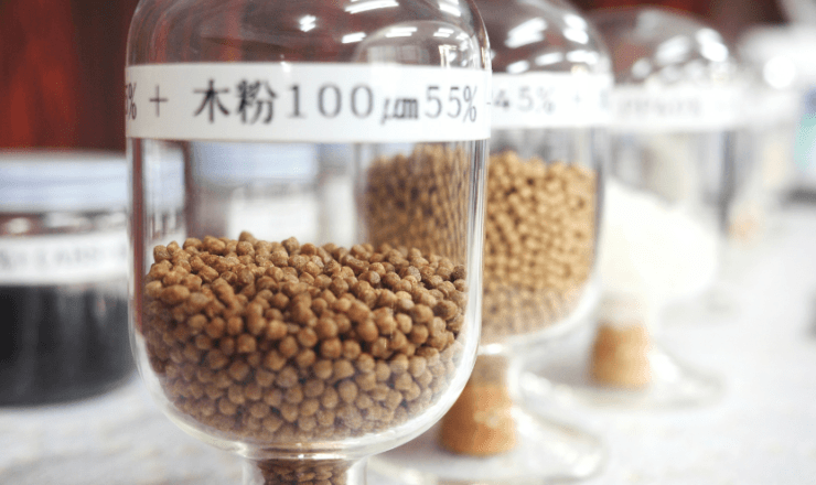 Jars containing plastic and wood powder pellets, representing CTE’s sustainable material compounding expertise, labeled with particle sizes and concentrations.