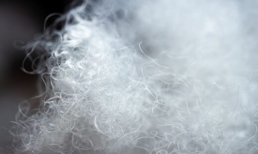 Close-up of shredded plastic fiber scrap with extremely low bulk density, illustrating air-rich nylon fibers used in recycling and extrusion processing.