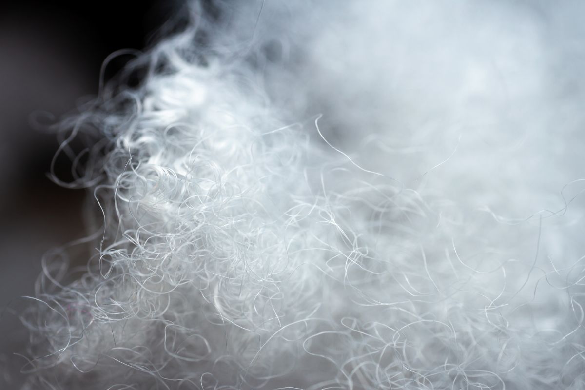 Close-up of shredded plastic fiber scrap with extremely low bulk density, illustrating air-rich nylon fibers used in recycling and extrusion processing.