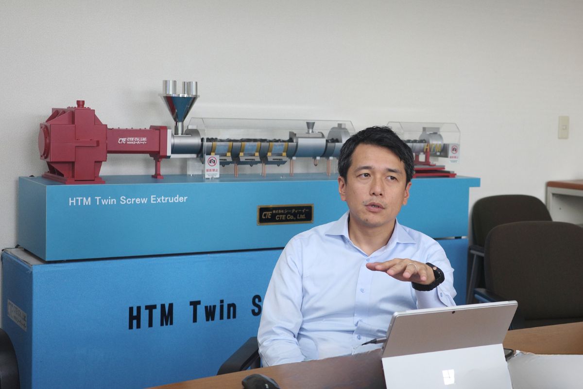 Masato Ito, leading a discussion on advanced extrusion solutions, seated in front of the HTM Twin Screw Extruder at CTE's office.